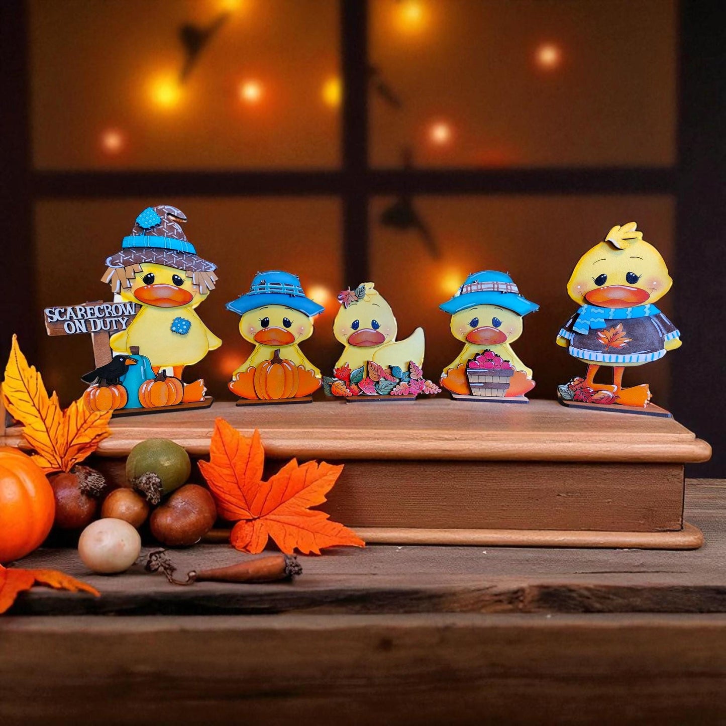 A group of colorful duck figurines, including a scarecrow, are arranged on a wooden surface, surrounded by autumn leaves and other seasonal decorations.