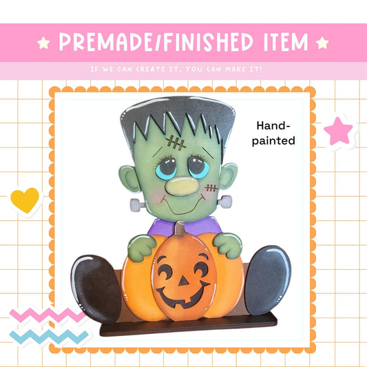 a Halloween-themed decoration with a carved pumpkin and a green-skinned, purple-dressed character resembling a Frankenstein monster.