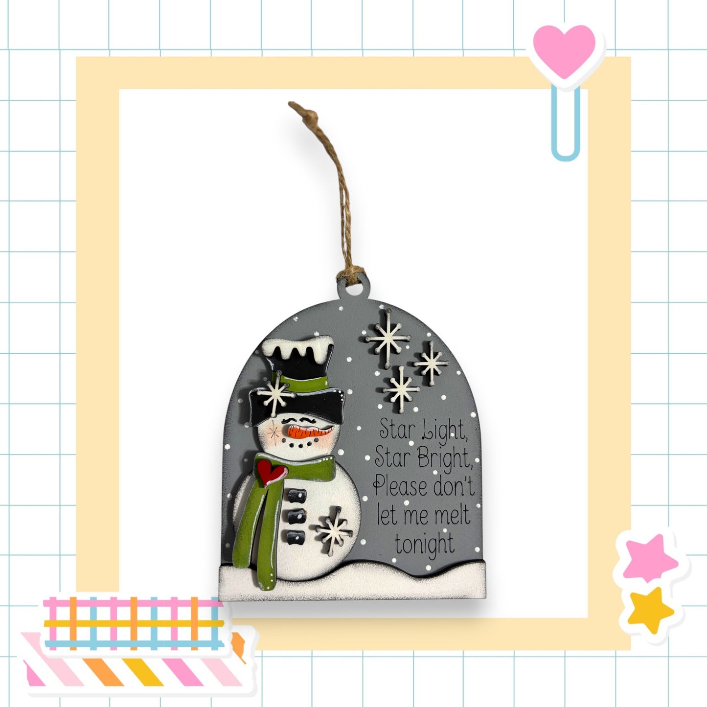 A snowman ornament with a heart-shaped tag hanging from it, set against a yellow and white checkered background.