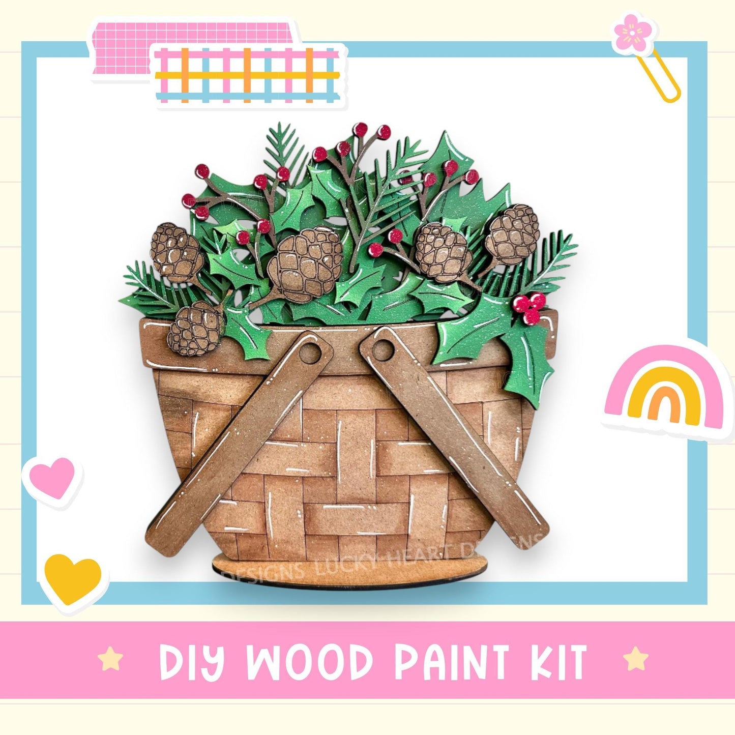 A DIY wood paint kit featuring a wooden basket filled with pine cones, holly leaves, and berries, with a rainbow and hearts in the background.