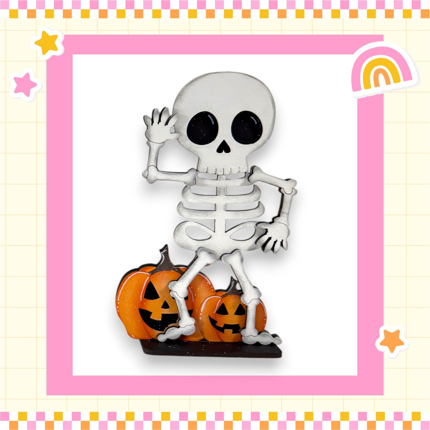 A skeleton figurine is standing on top of two carved pumpkins, with a rainbow and stars surrounding the scene.