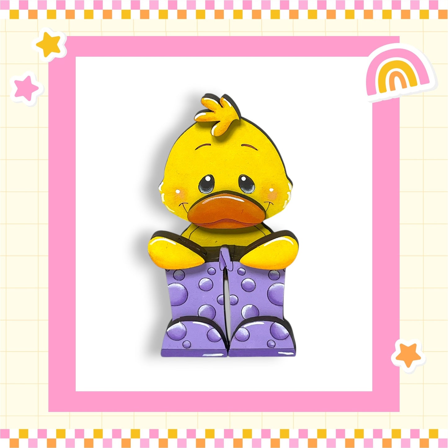 A yellow duck wearing purple polka dot boots is sitting in a pink and yellow checkered frame.