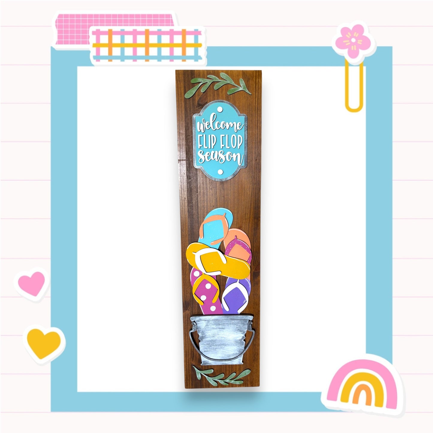 a wooden sign with a colorful design, surrounded by various decorative elements such as hearts, a flower, and a rainbow.