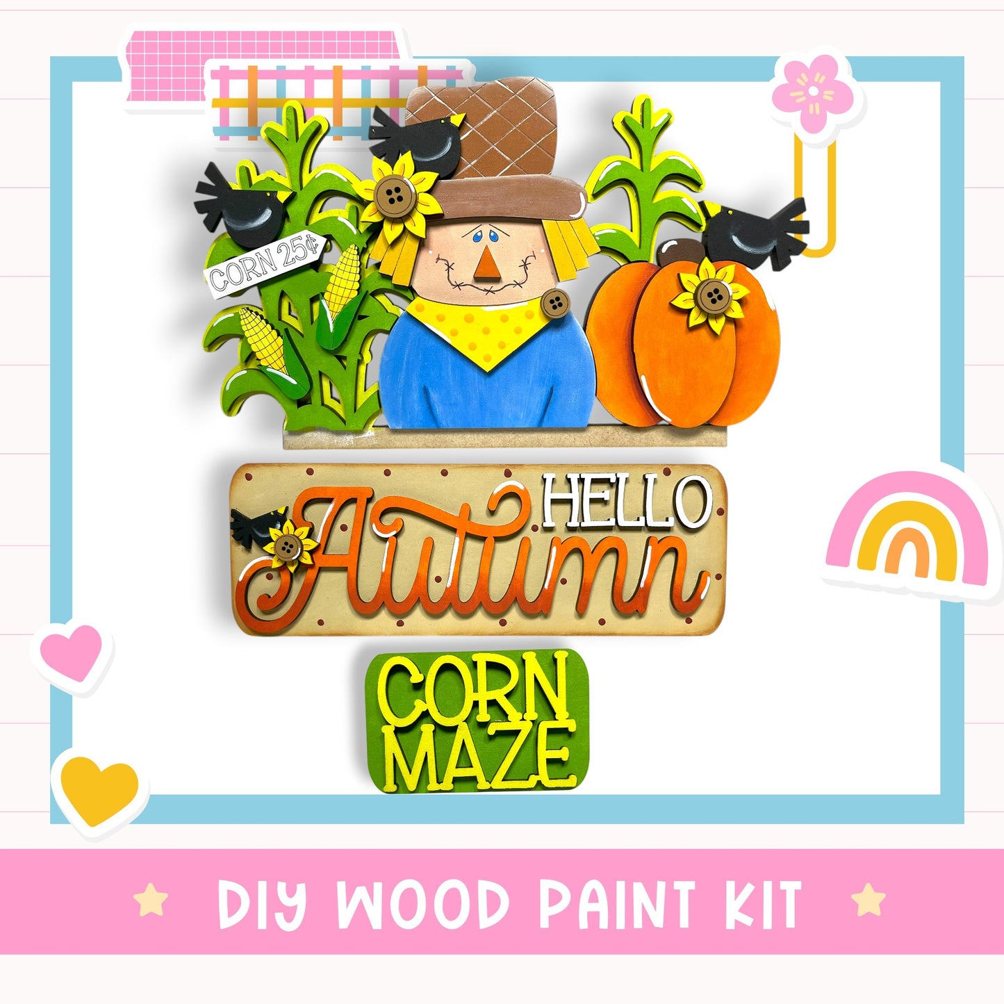 The image is a colorful and whimsical DIY wood paint kit featuring a scarecrow, pumpkins, and a corn maze, all set against a background with a rainbow and hearts.