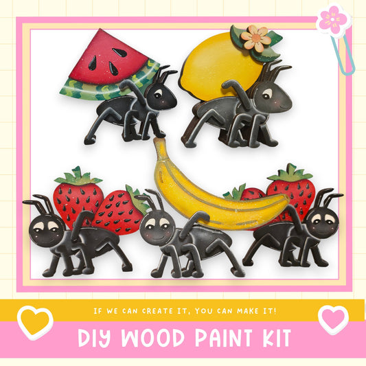 The image is a colorful and playful DIY wood paint kit featuring various cartoon-style insects and fruits, such as ants, a banana, and strawberries.
