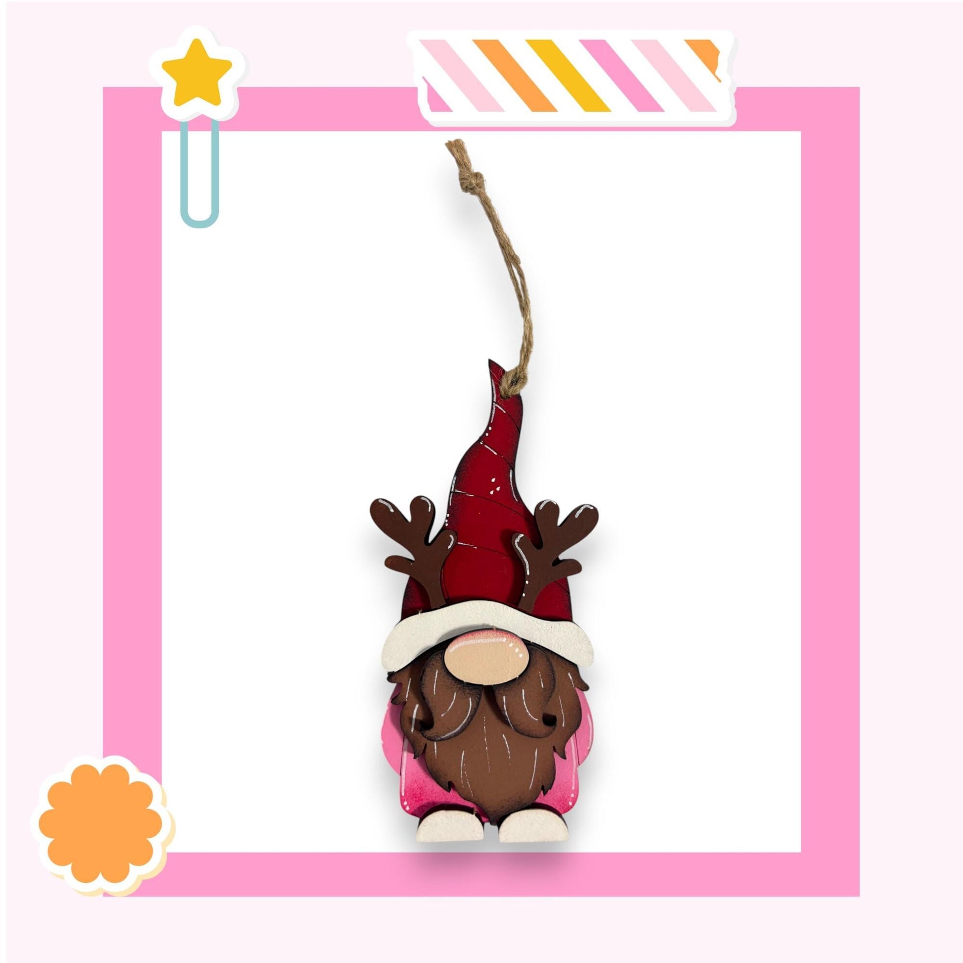 A gnome ornament with antlers and a red hat is displayed against a pink background.