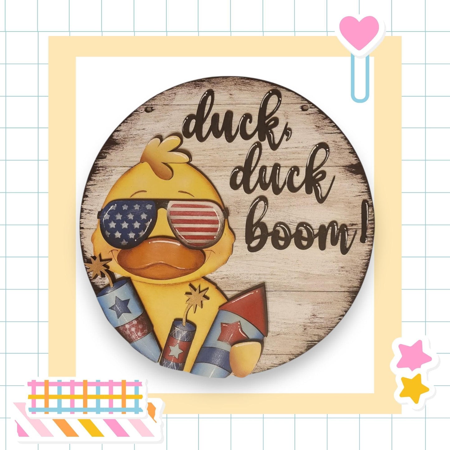 A wooden sign with a duck wearing sunglasses and holding fireworks, accompanied by the text "duck, duck boom!"