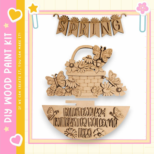 a wooden sign with the word "SPRING" written on it, along with various decorative elements such as butterflies and flowers. The sign appears to be a part of a larger wooden craft kit, as indicated by the text "My Wood Paint Kit" and "If we can create it, you can make it".