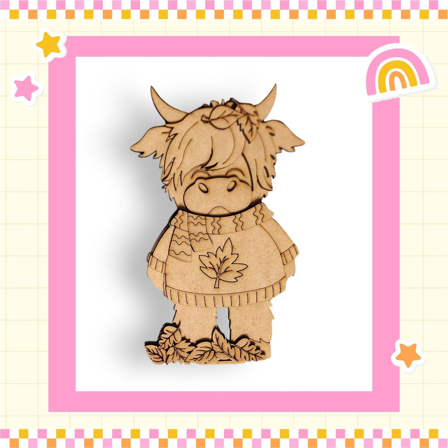 A wooden cutout of a cow wearing a sweater with a leaf design, set against a pink and yellow checkered background with stars and a rainbow.