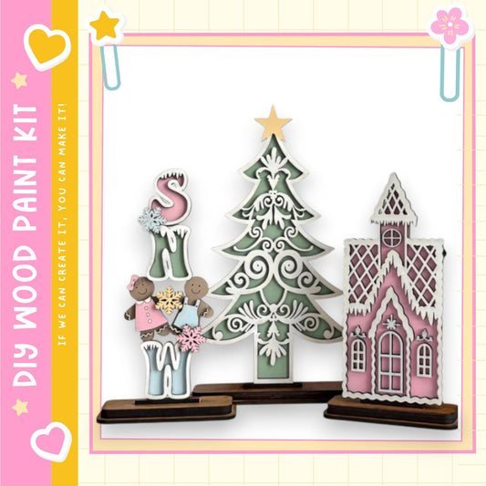 a wooden paint kit with various decorative elements, including a Christmas tree, a gingerbread house, and a snowman.