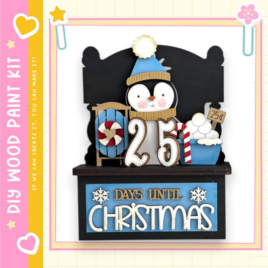 A wooden paint kit with a penguin figure and a sign that says "25 DAYS UNTIL CHRISTMAS".