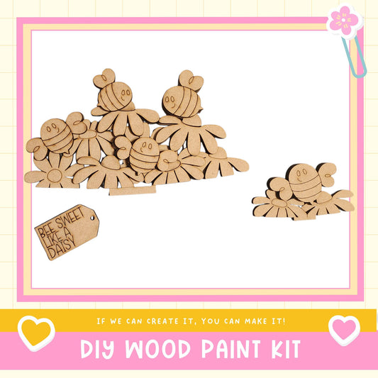 The image is a DIY wood paint kit featuring a collection of wooden bee-shaped figures and a tag that reads "Bee Sweet Like a Daisy".