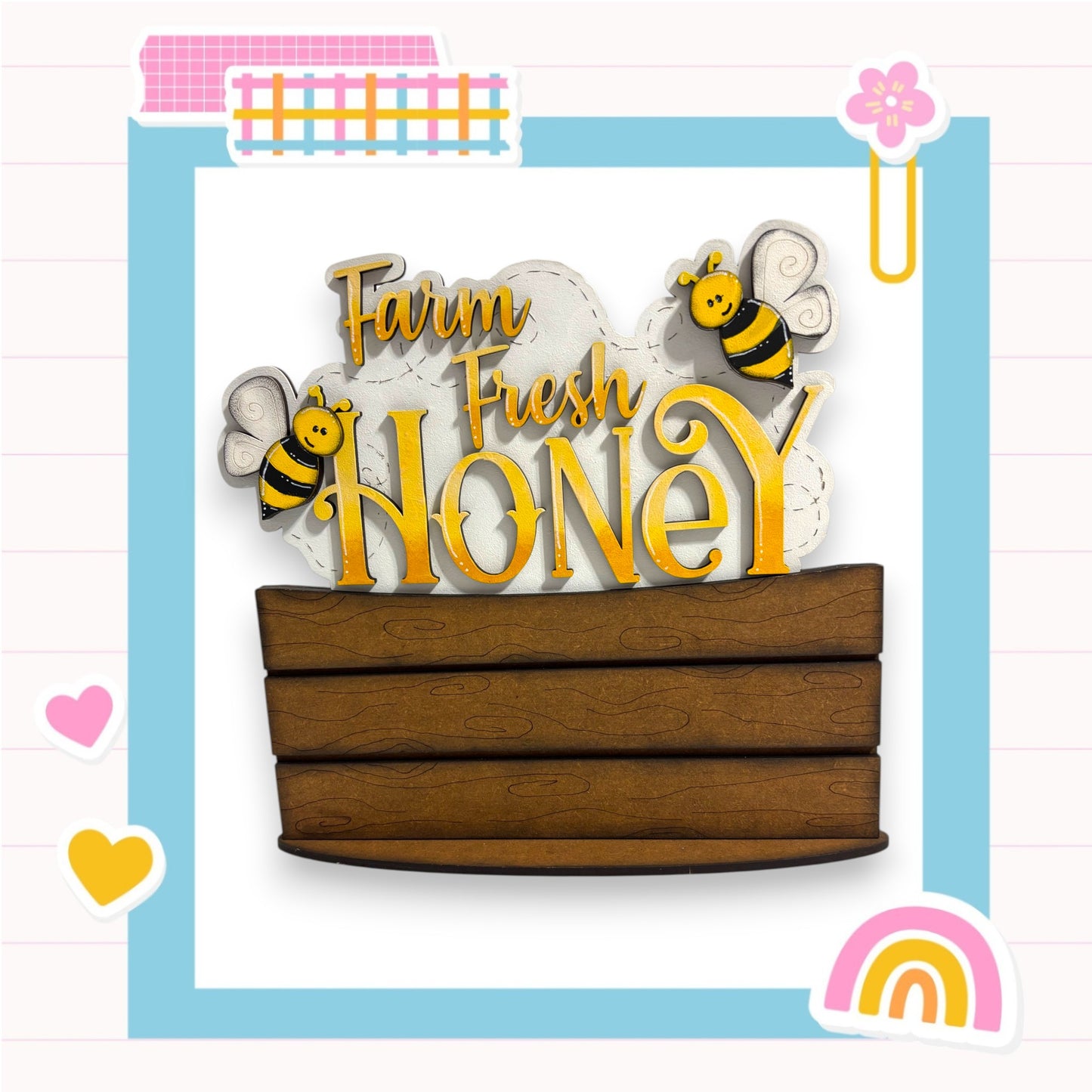 a wooden box with the words "Farm Fresh Honey" written on it, along with two cartoon bees. The background is a light blue color with a pink and white checkered pattern.