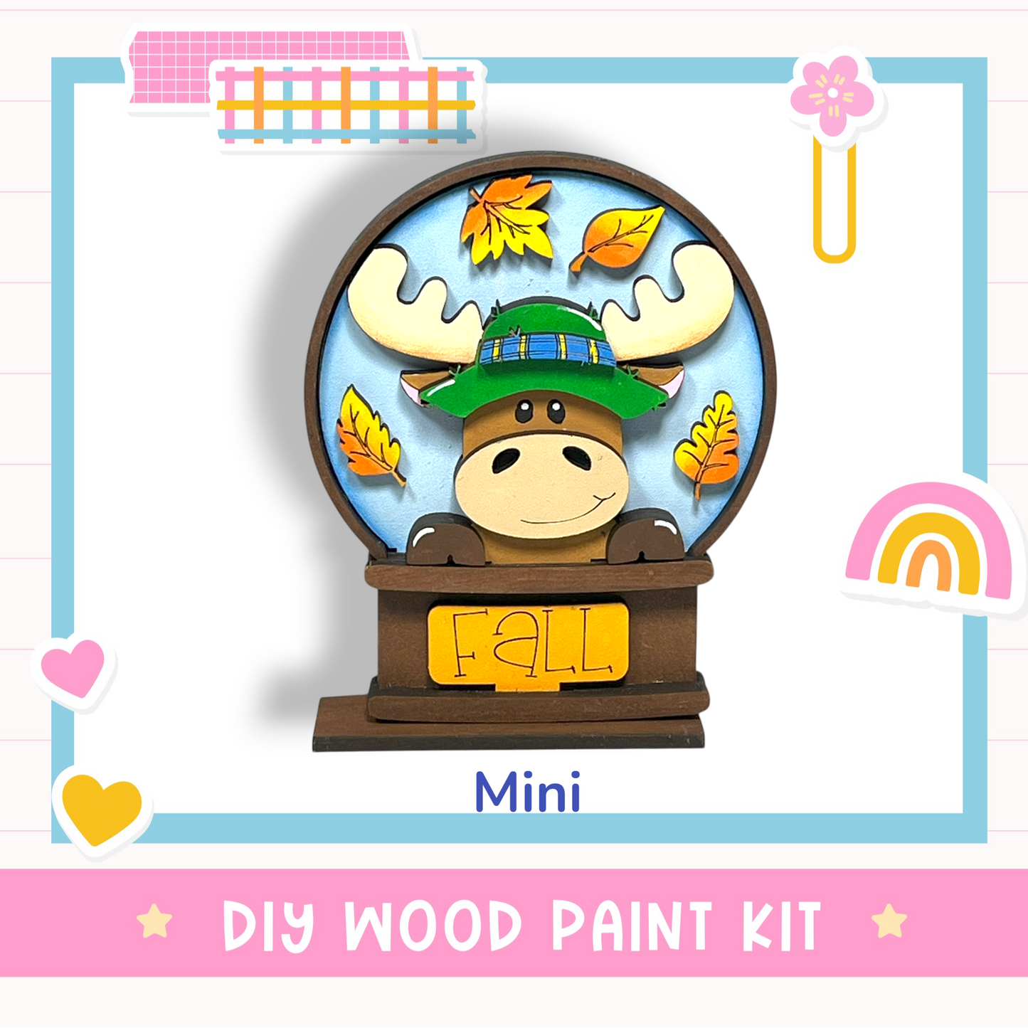 The image is a colorful and whimsical DIY wood paint kit featuring a cartoon moose wearing a green hat and surrounded by autumn leaves.