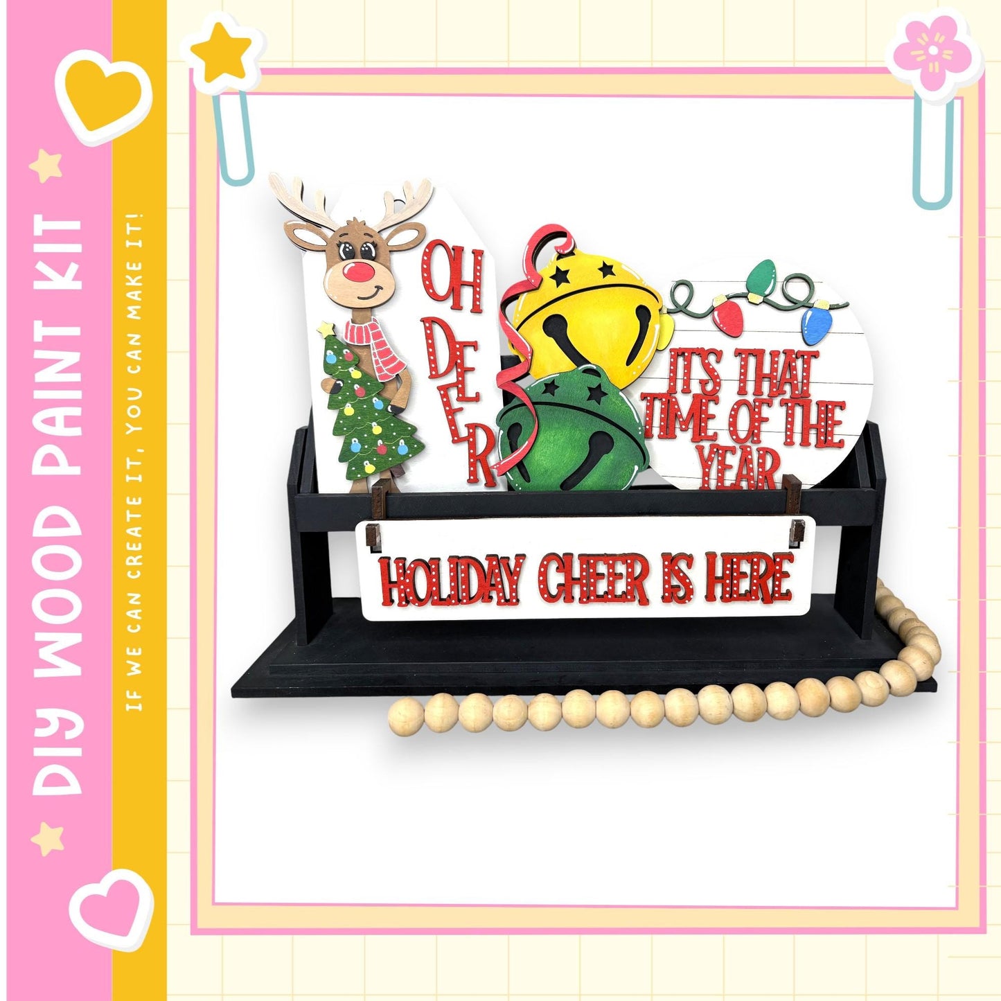 A festive holiday-themed display featuring a reindeer, a bell, and a sign that says "HOLIDAY CHEER IS HERE".