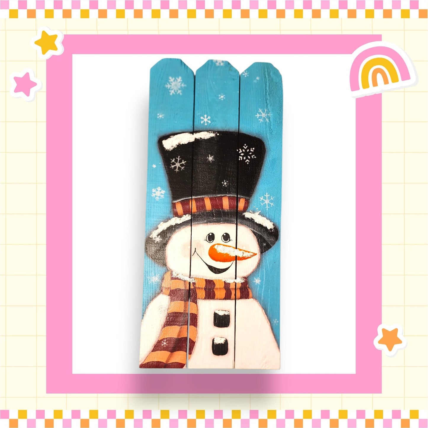 A wooden snowman with a black top hat and striped scarf, painted on a blue background with snowflakes.