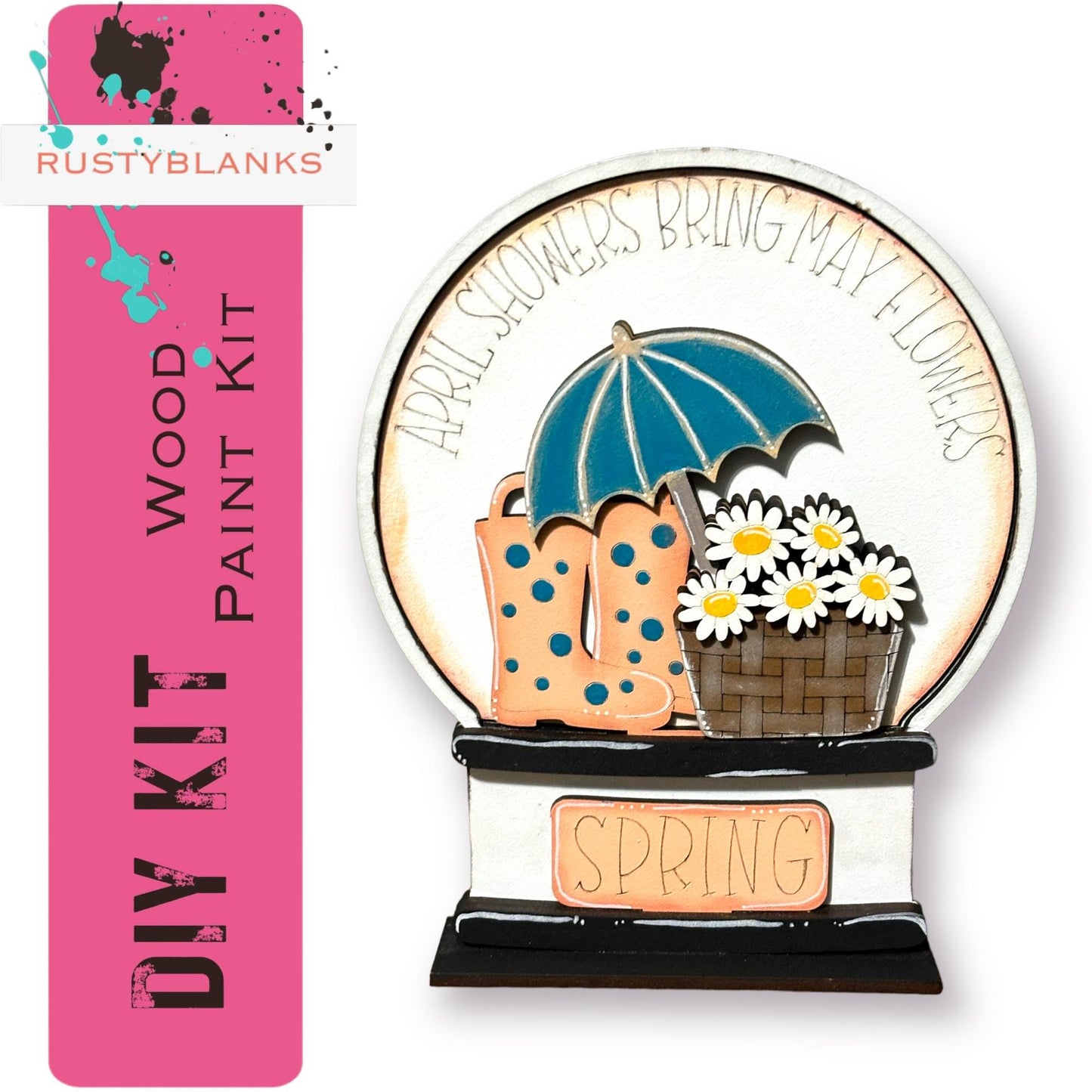 The image is a DIY kit for a paint kit that includes a wooden paint kit and a decorative piece featuring a blue umbrella, a basket of flowers, and a pair of rain boots.