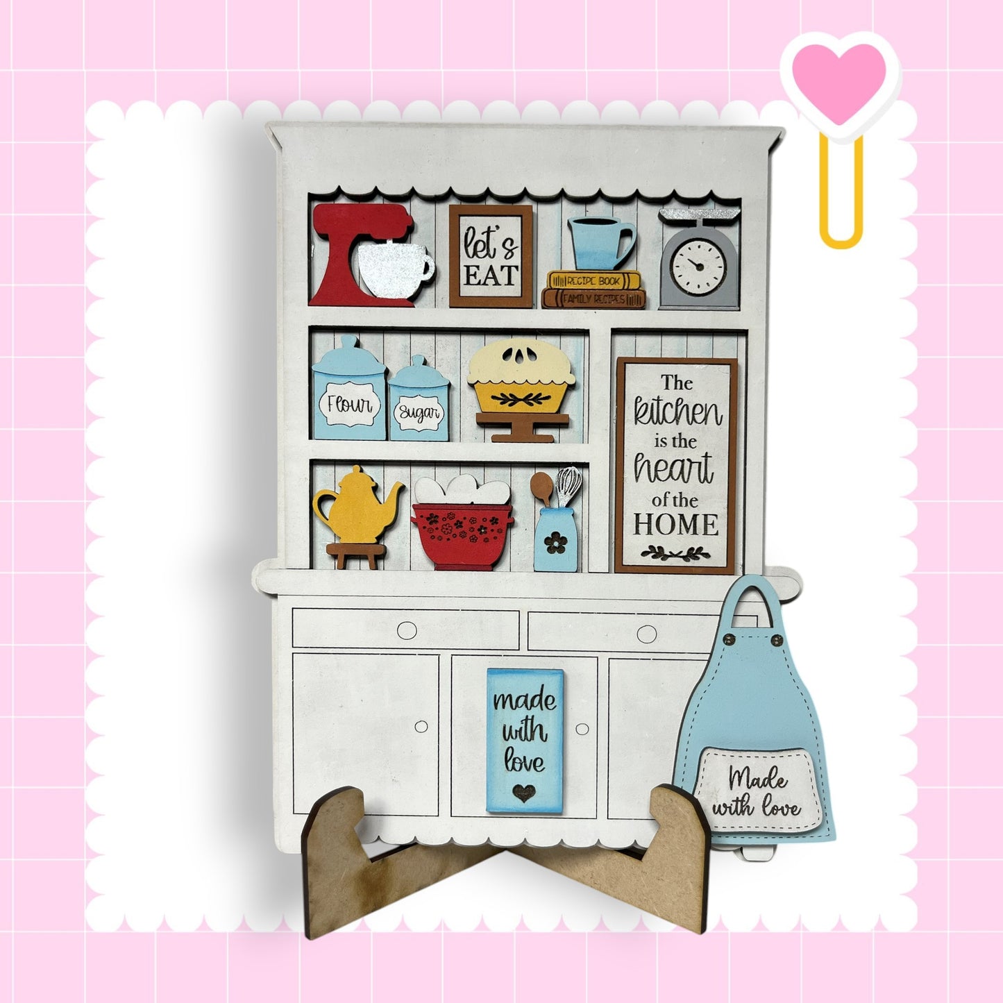 A wooden kitchen cabinet with various kitchen items and a heart-shaped magnet on the side.