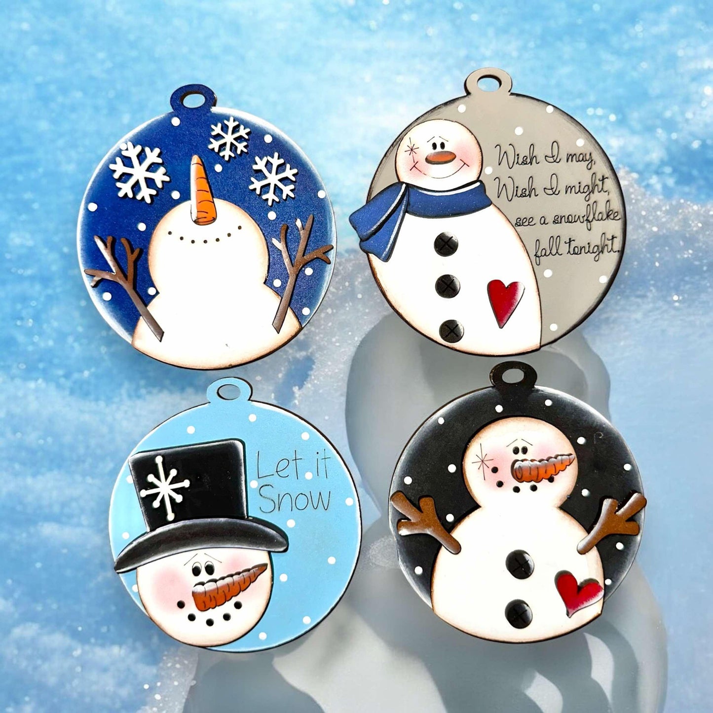 three snowmen wearing hats and scarfs on a snow covered surface