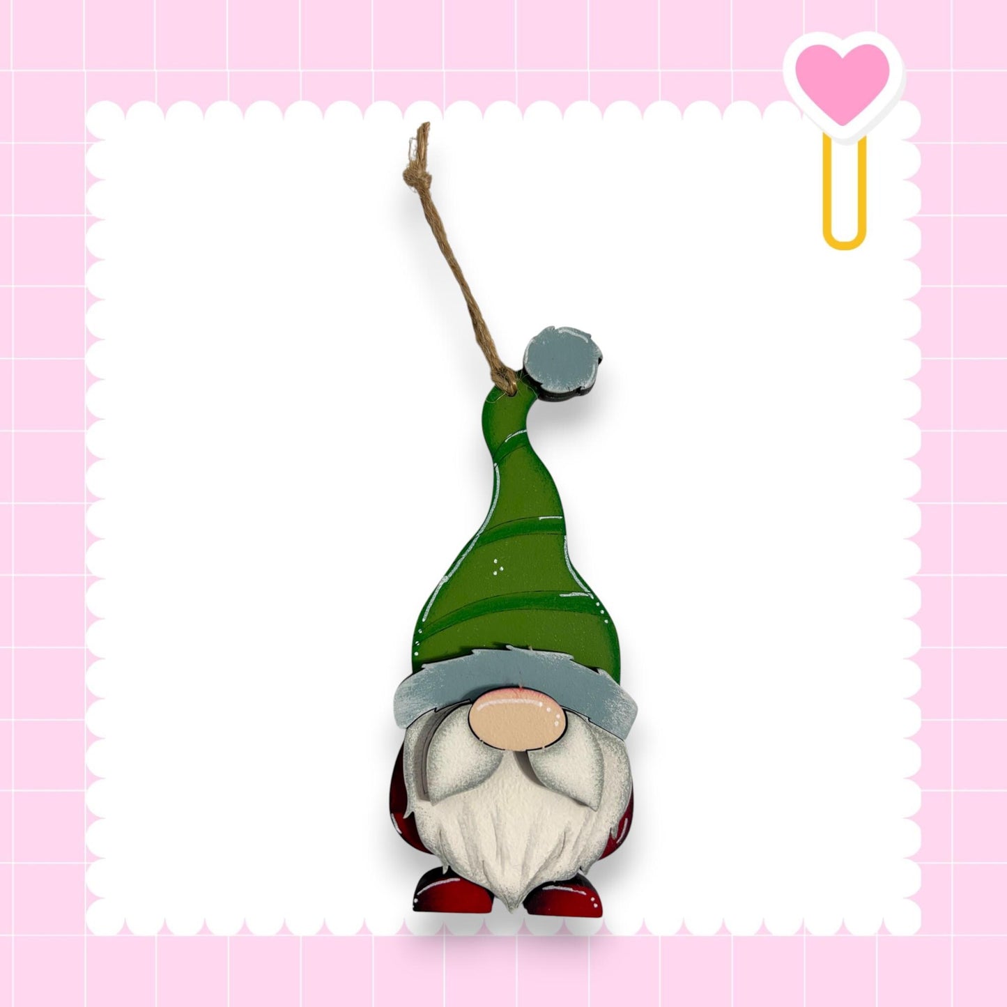 A gnome figurine wearing a green hat and standing against a pink background with a scalloped edge.