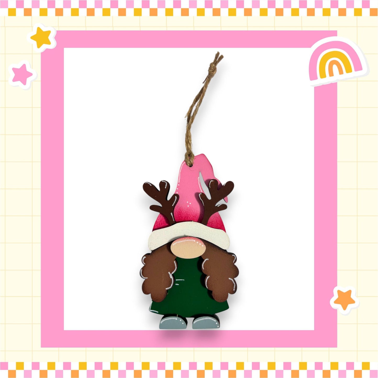 A pink and white ornament featuring a gnome-like figure with antlers and a green dress, hanging from a string.