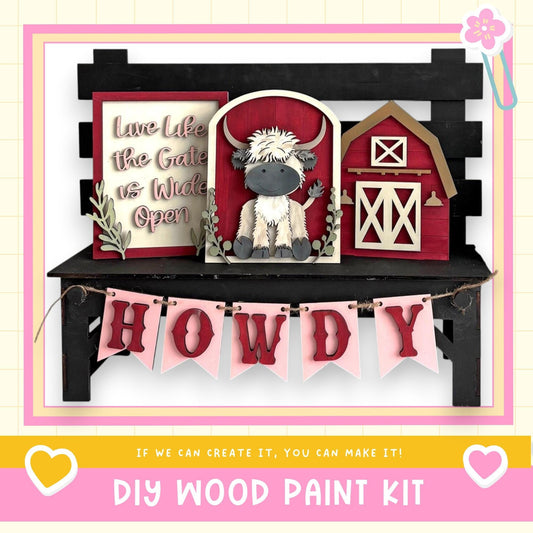 a DIY wood paint kit with a wooden bench, a wooden barn, and a wooden cow. The kit includes a banner with the word "HOWDY" and a heart symbol.