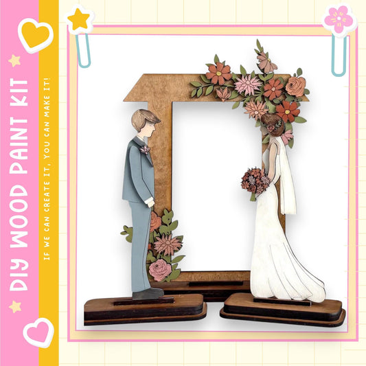 A wooden frame with a bride and groom figure inside, surrounded by flowers.