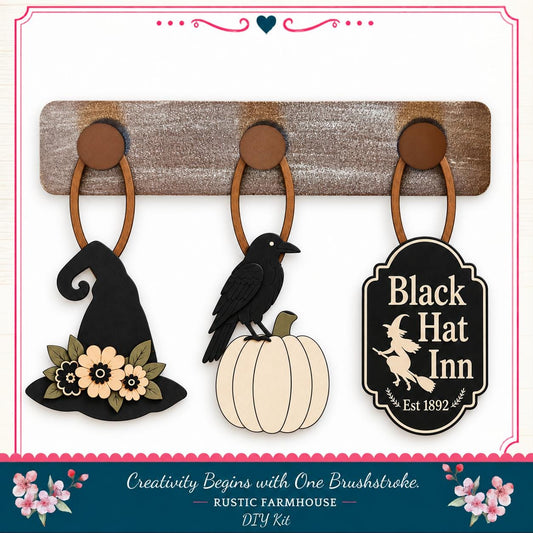 a rustic farmhouse-style DIY kit with three wooden wall hangings and a black witch's hat, a pumpkin, and a sign for the Black Hat Inn.