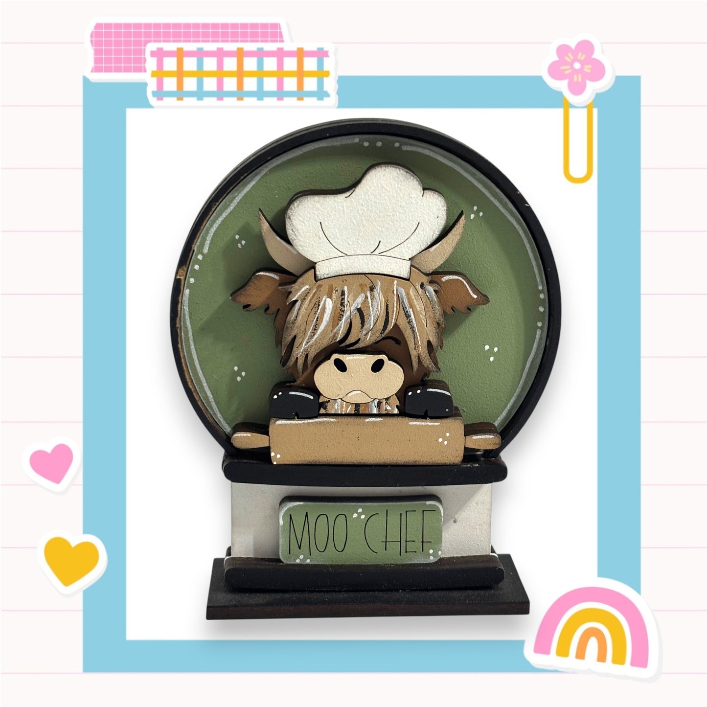 A wooden figurine of a cow wearing a chef's hat, sitting on a wooden table with the words "Moo CHEF" written on it.
