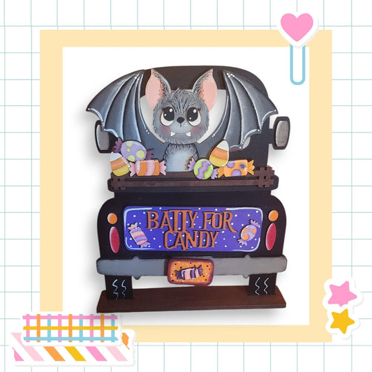 A wooden truck decorated with a bat and various Halloween-themed items, including candy and a sign that says "Bally for candy".