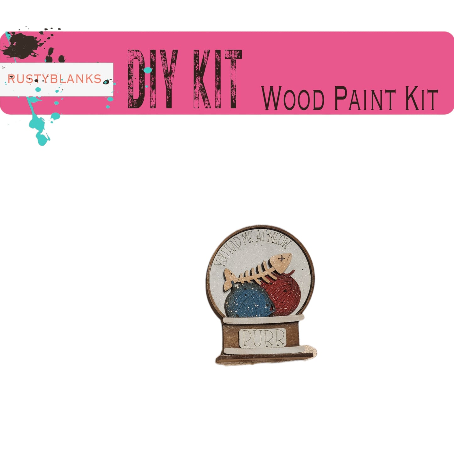 The image is a pink banner with the text "DIY KIT" and "WOOD PAINT KIT" written on it. Below the banner, there is a small wooden snow globe with a cat inside.