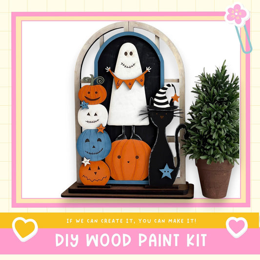 A DIY wood paint kit featuring a Halloween-themed display with a ghost, jack-o-lanterns, a cat, and a potted plant.