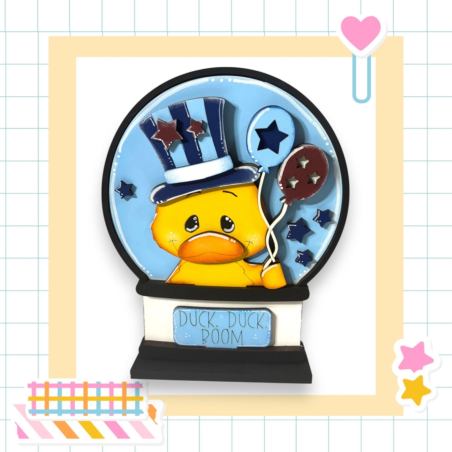 A yellow duck wearing a top hat and holding a star-shaped balloon is depicted in a blue snow globe, with the text "Duck Duck Boom" written on the base.