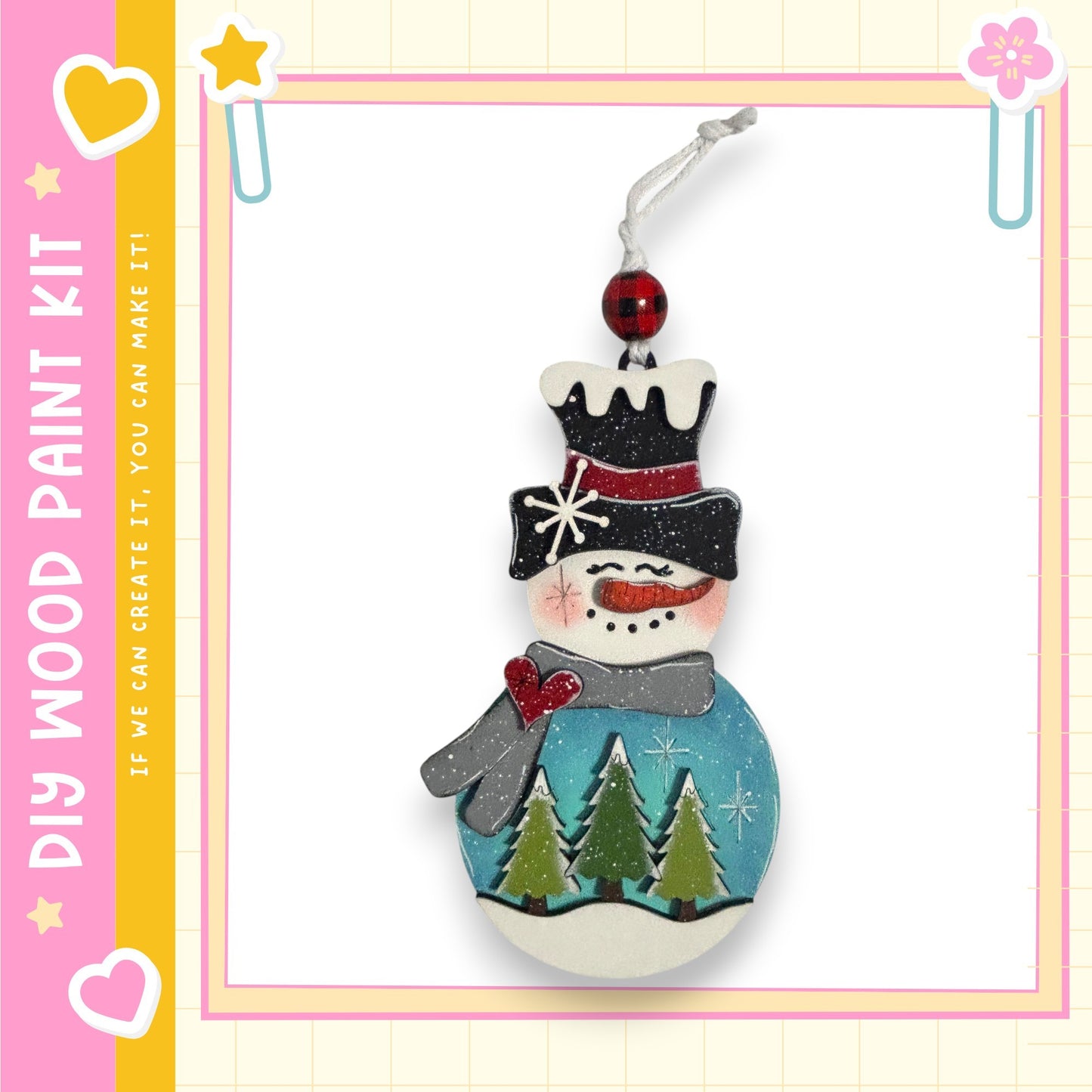 A wooden snowman ornament with a red bow, a black top hat, and a blue scarf, decorated with green pine trees and a blue snowman.