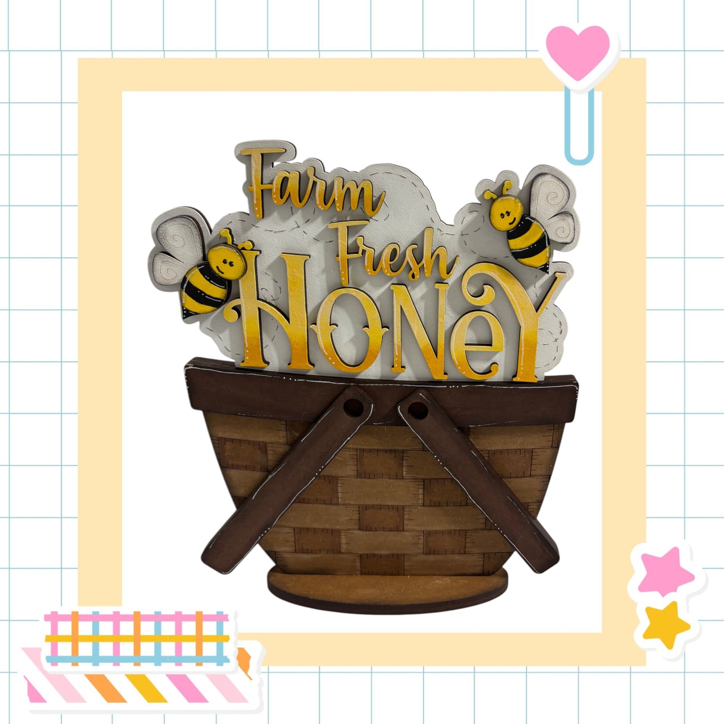 a wooden basket with the words "Farm Fresh Honey" written on it, along with two cartoon bees. The basket is placed within a decorative frame, and there are additional elements such as a heart and stars surrounding the image.