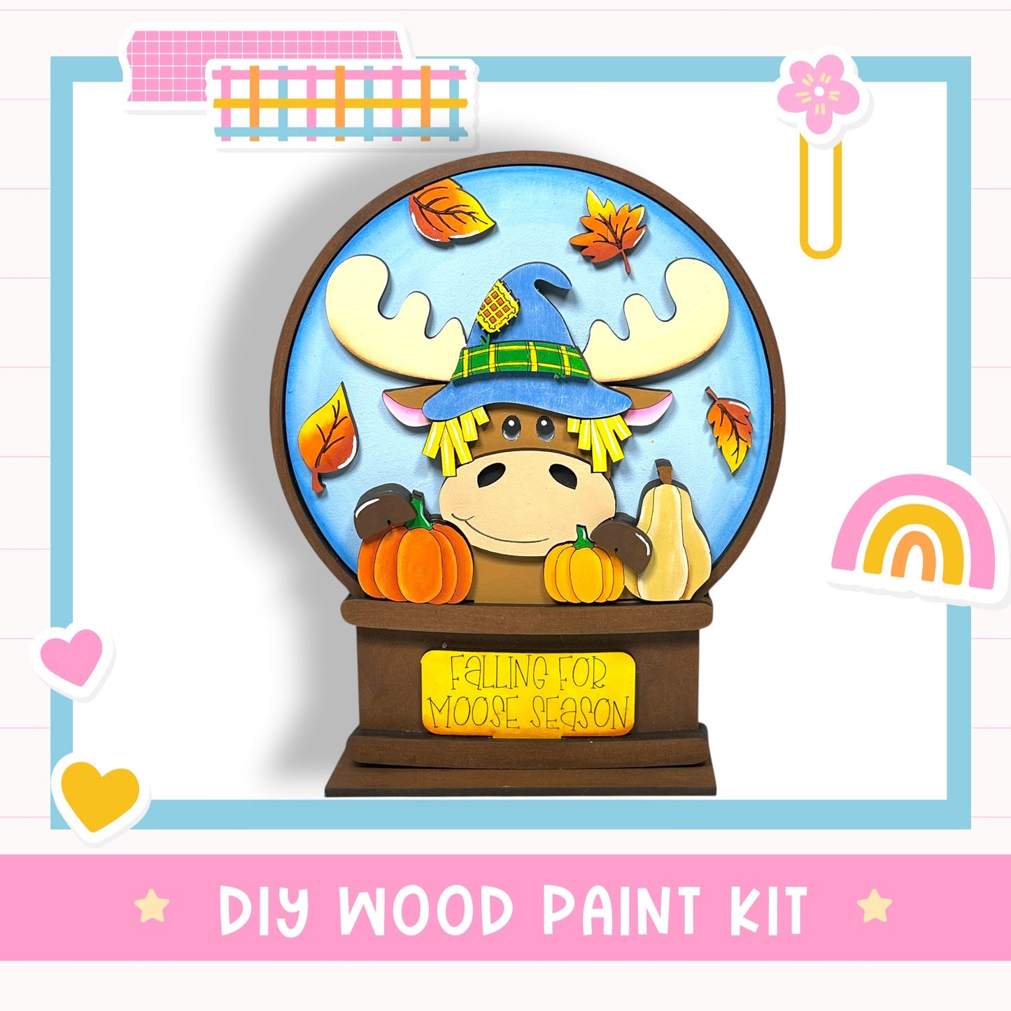 A DIY wood paint kit featuring a cartoon moose wearing a witch's hat and surrounded by autumn leaves and pumpkins, with a sign that says "FALLING FOR MOOSE SEASON".