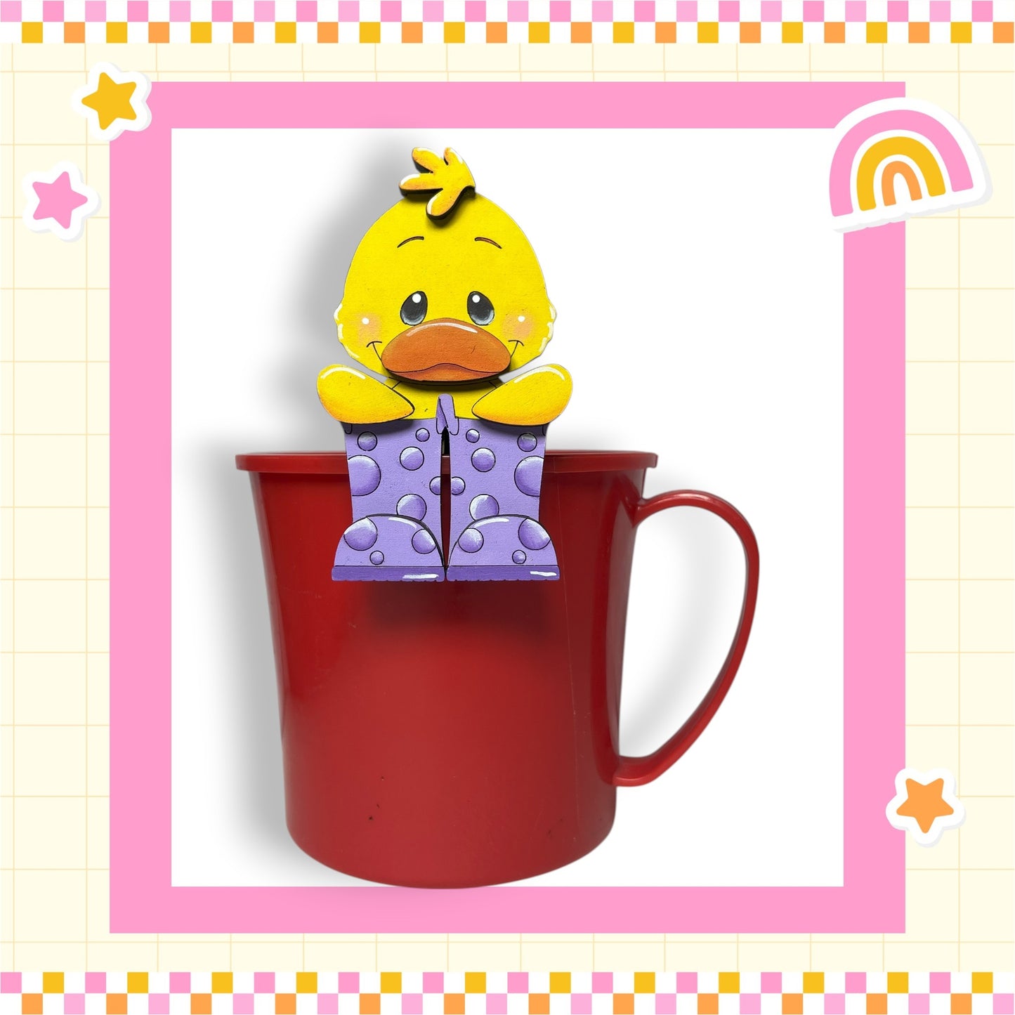 A yellow duck figurine is sitting inside a red mug, which is placed on a pink and white checkered background.