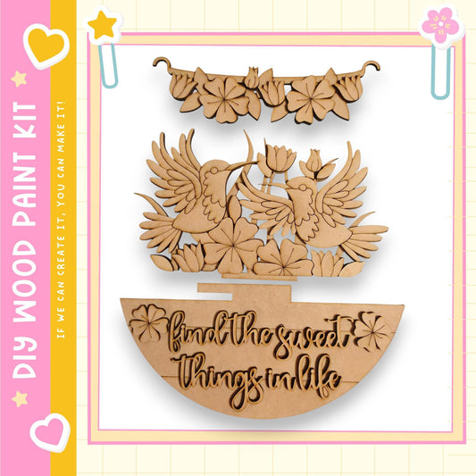 a wooden craft kit with a decorative design, including a pair of wooden birds, flowers, and a text message that reads "Find the sweet things in life".