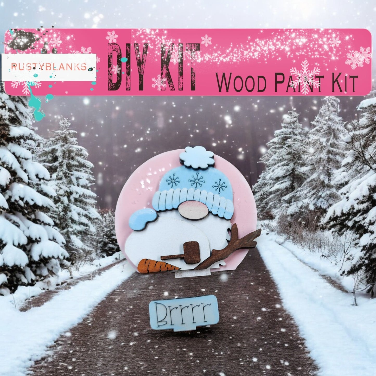 A DIY wood paint kit for creating a snowman, featuring a pink snowman figure and a snowman-themed sign. The background shows a snowy landscape with pine trees.