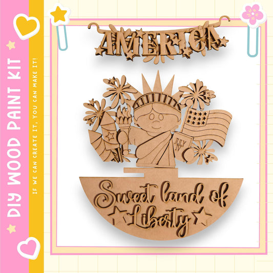 The image is a wooden craft kit featuring a wooden figure of a woman holding a torch and a banner that says "America" and "Sweet land of Liberty".