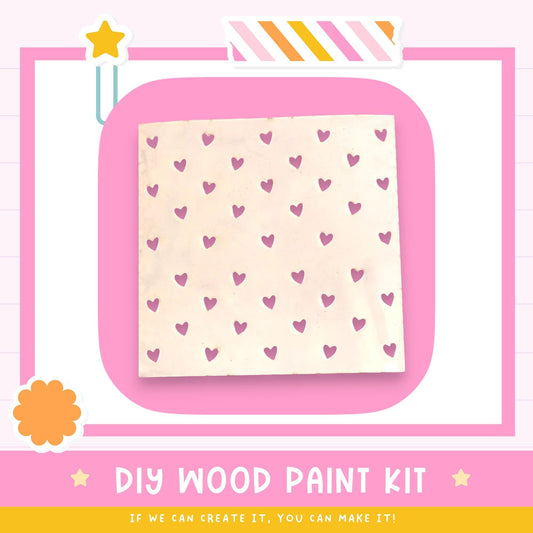 The image is a DIY wood paint kit advertisement, featuring a pink background with a white square containing a pattern of pink hearts. The text below the image encourages viewers to "If we can create it, you can make it!"