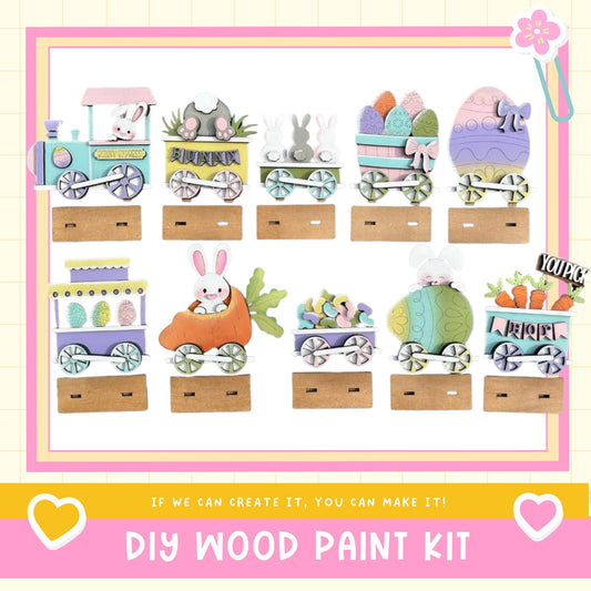 The image is a collage of nine Easter-themed wooden train car decorations, each featuring a different Easter egg and bunny design. The decorations are displayed on wooden platforms, and the image includes text that reads "DIY WOOD PAINT KIT" and "IF WE CAN CREATE IT, YOU CAN MAKE IT!"