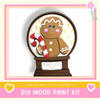 A gingerbread man figure holding a candy cane, with the text "BAKED WITH LOVE" on a wooden base, and the text "DIY WOOD PAINT KIT" below.