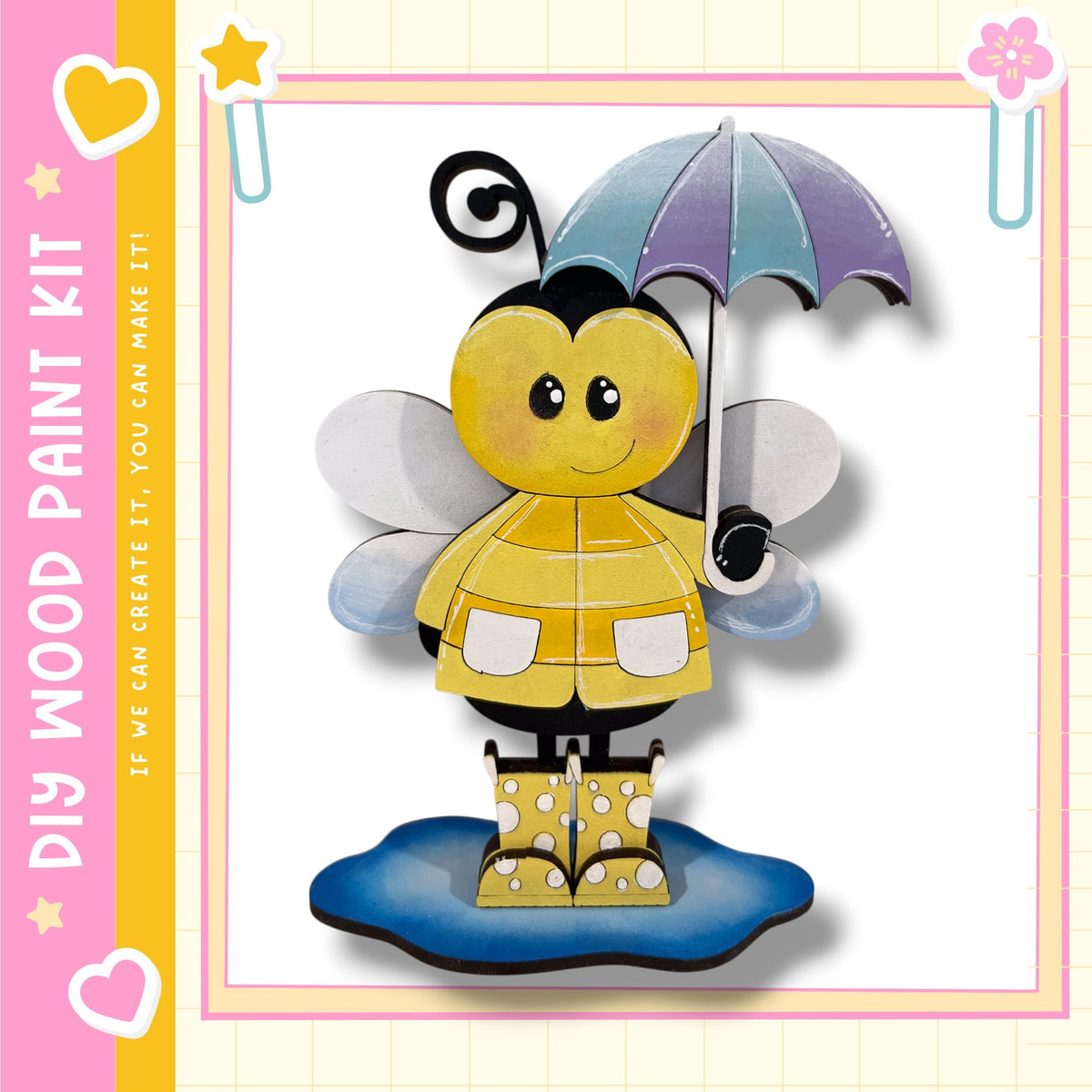 A cheerful yellow bee holding an umbrella and wearing rain boots stands on a puddle, surrounded by a pink and yellow border with hearts and stars.