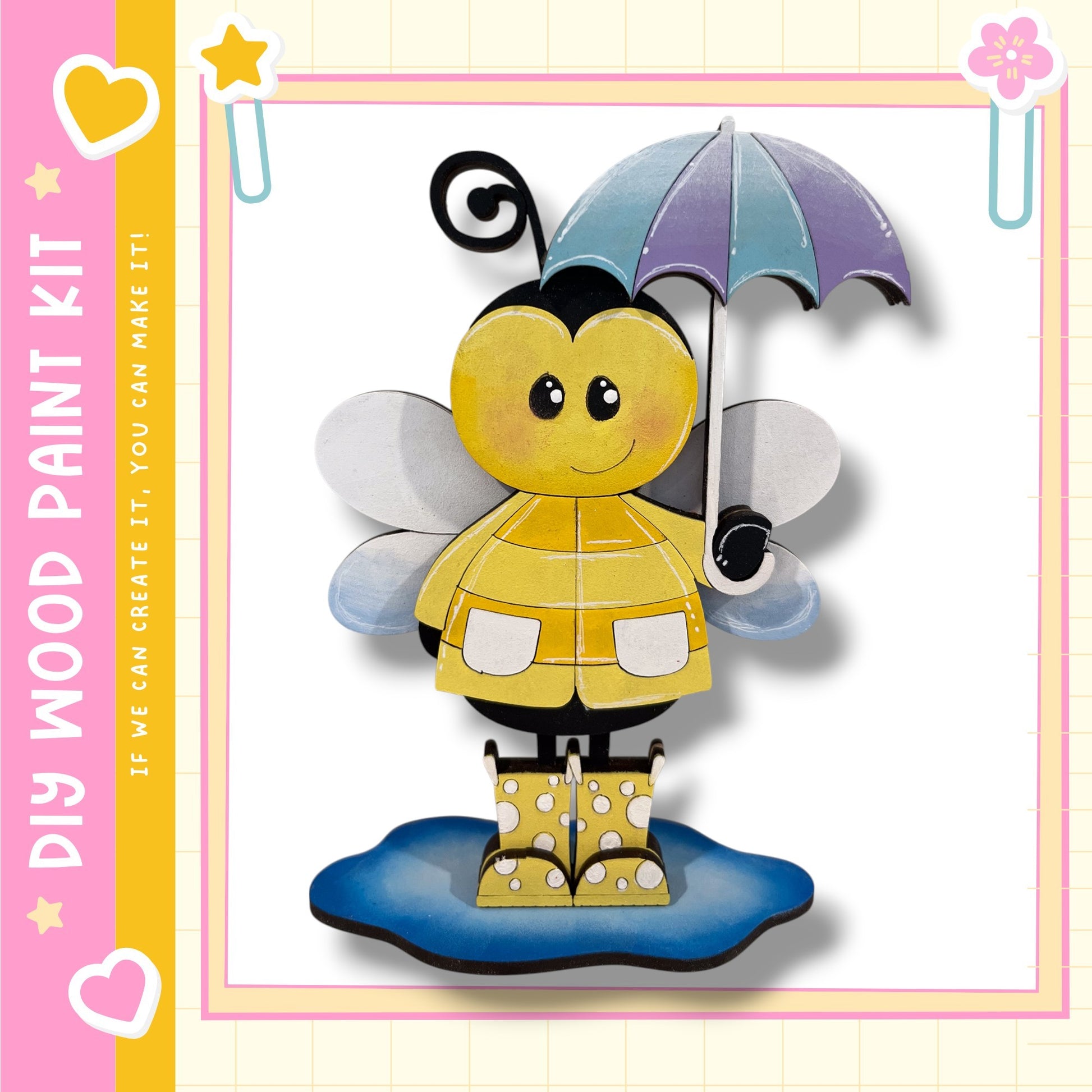 A cheerful yellow bee holding an umbrella and wearing rain boots stands on a puddle, surrounded by a pink and yellow border with hearts and stars.