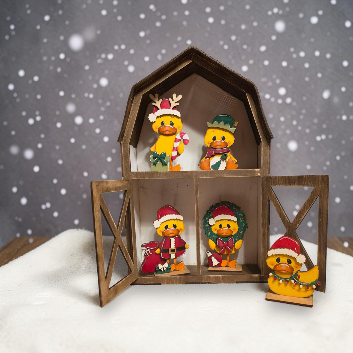 A wooden toy barn with four small duck figurines inside, set against a snowy background with falling snowflakes.