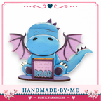 A handcrafted wooden dragon figurine holding a sign that says "Let the world hear you Roar".