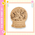 A wooden snow globe with a decorative design, including a hat, flowers, and the text "St. Patrick's Day".