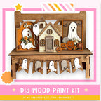 The image is a DIY wood paint kit for creating Halloween decorations, including a wooden house, ghost figures, and a banner with ghostly figures.