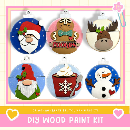 The image is a collage of six wooden ornaments, each depicting a different festive character or decoration, including Santa Claus, gingerbread cookies, a moose, a gnome, a snowman, and a cup of hot chocolate.